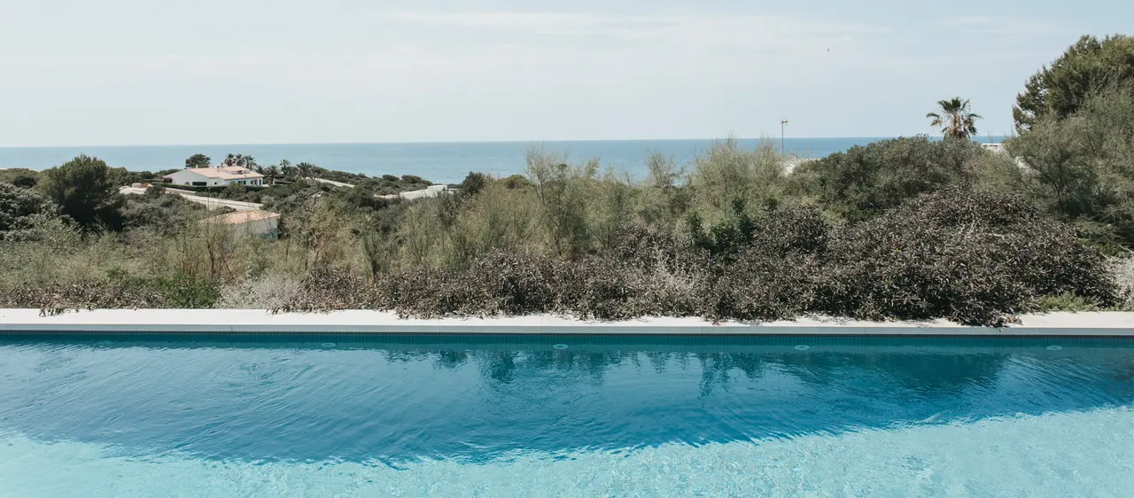 Piscina sobre el paisaje costero de Binibeca con el horizonte del mar al fondo, Menorca
